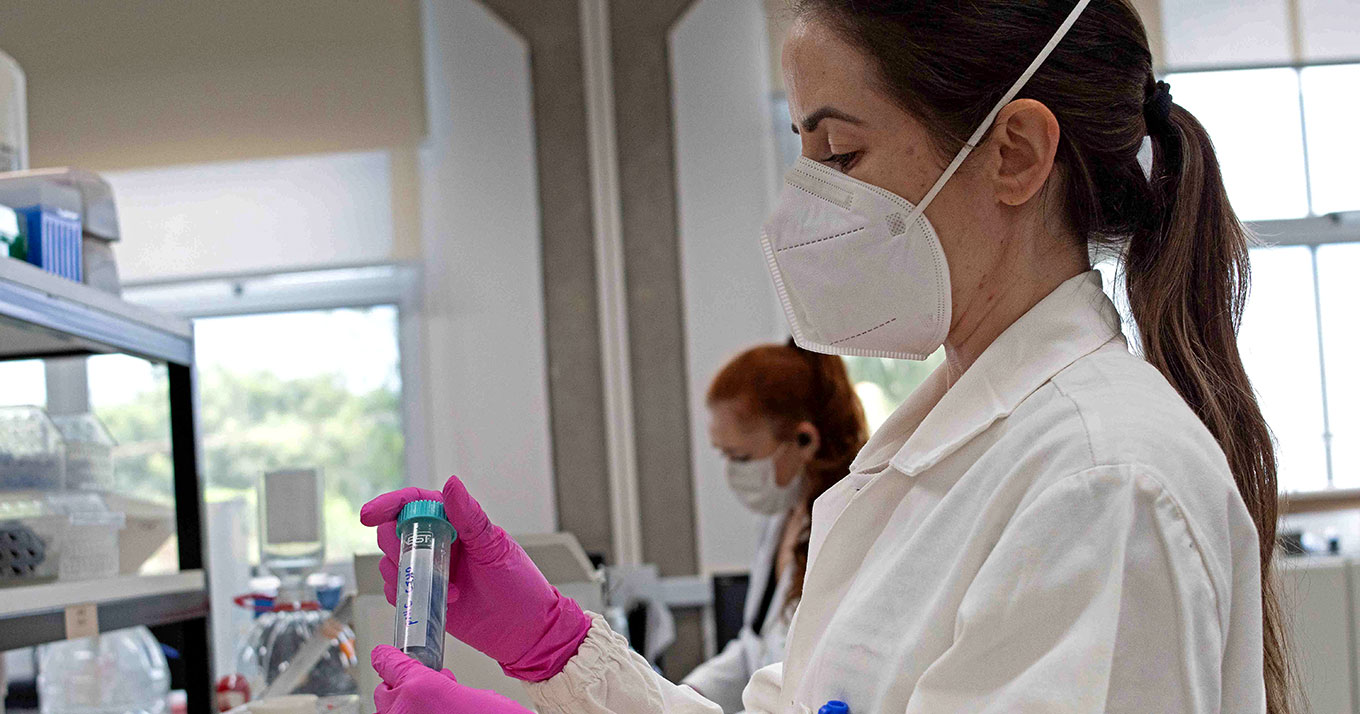 Foto de uma mulher manuseando uma pipeta em um laboratório de pesquisa