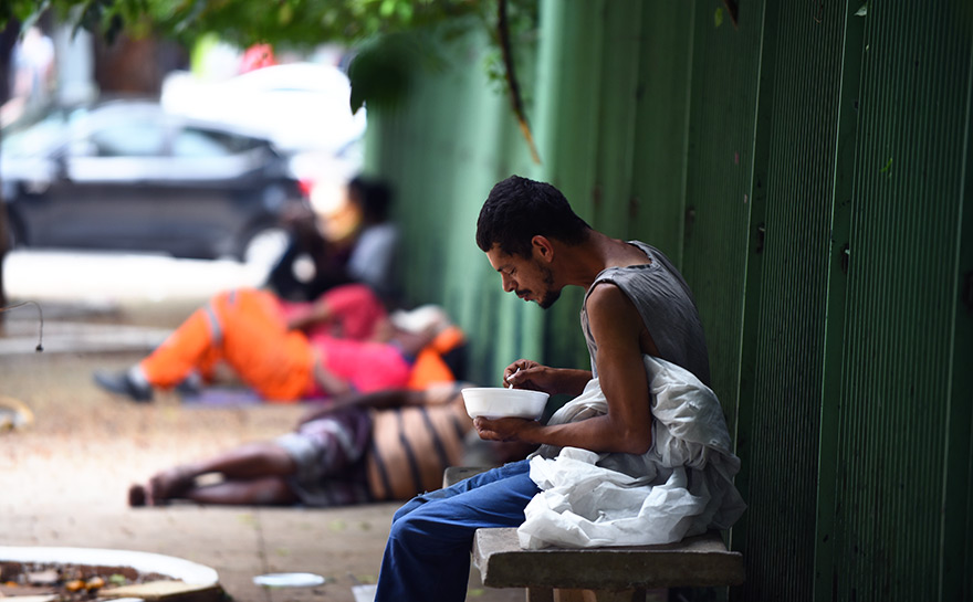 Pessoa em situação de rua durante refeição no centro de São Paulo; acesso à comida ainda é incerto 