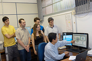 O professor Jun Takahashi (sentado) com alunos do IFGW e junto a detector de silício desenvolvido em experimento no LHC: novas descobertas à vista (Foto: Antoninho Perri) 