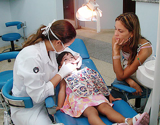 A cirurgiã-dentista Annicele da Silva Andrade (à esq.) atende criança: tratamento deve ser iniciado antes do surto de crescimento da puberdade (Foto: Divulgação)